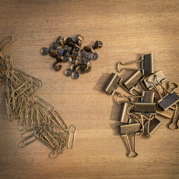 antique brass tacks antiqued binder clips and brass paper clips on rustic wood background