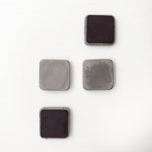 4 square shaped concrete magnets arranged in a stepped pattern with two flipped over showing large vinyl magnet on back