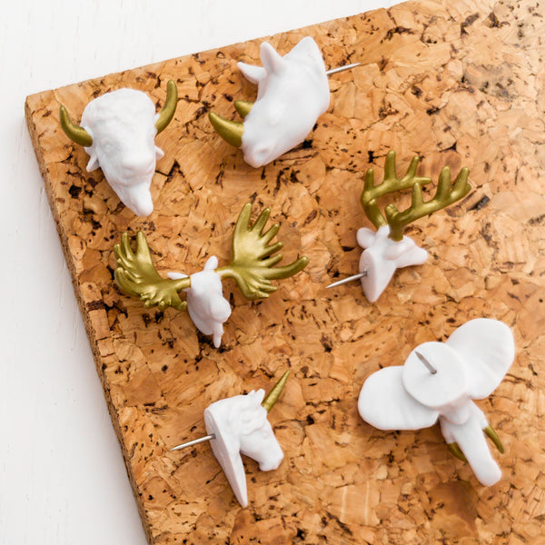6 white and gold animal head push pins on cork bulletin board